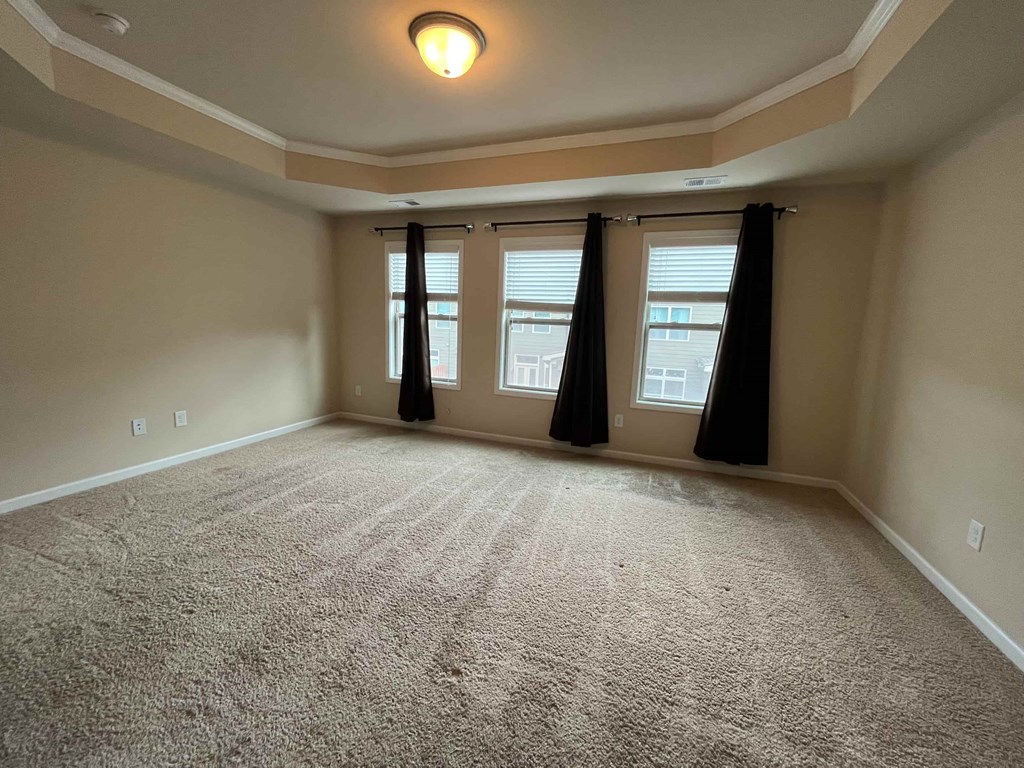 an empty living room with windows and carpet