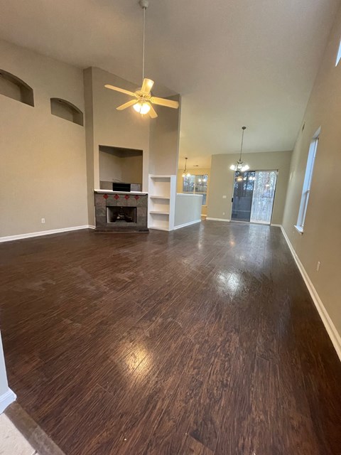 an empty living room with wood floors and a ceiling fan