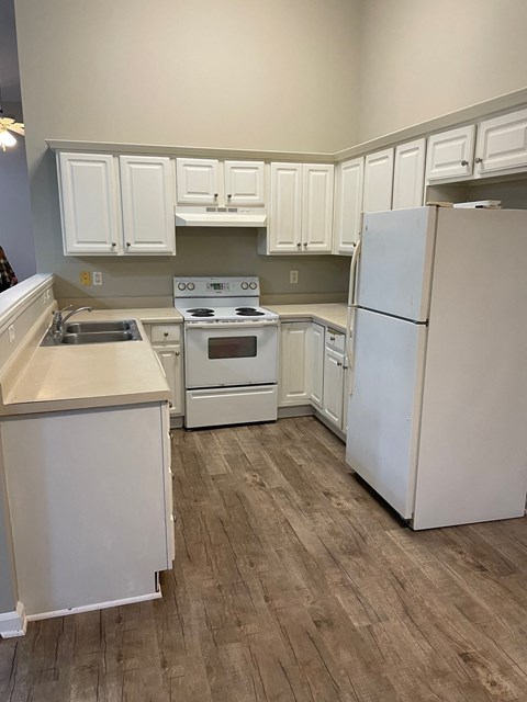 a kitchen with white cabinets and appliances and a refrigerator