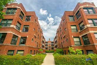 a row of red brick apartment buildings with a pathway between them