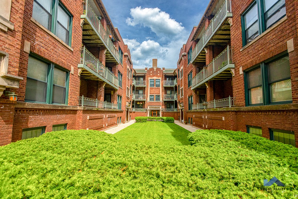 the courtyard of an apartment building with green grass