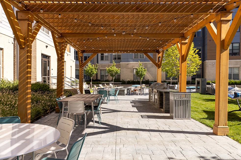 a patio with tables and chairs under a wooden pavilion