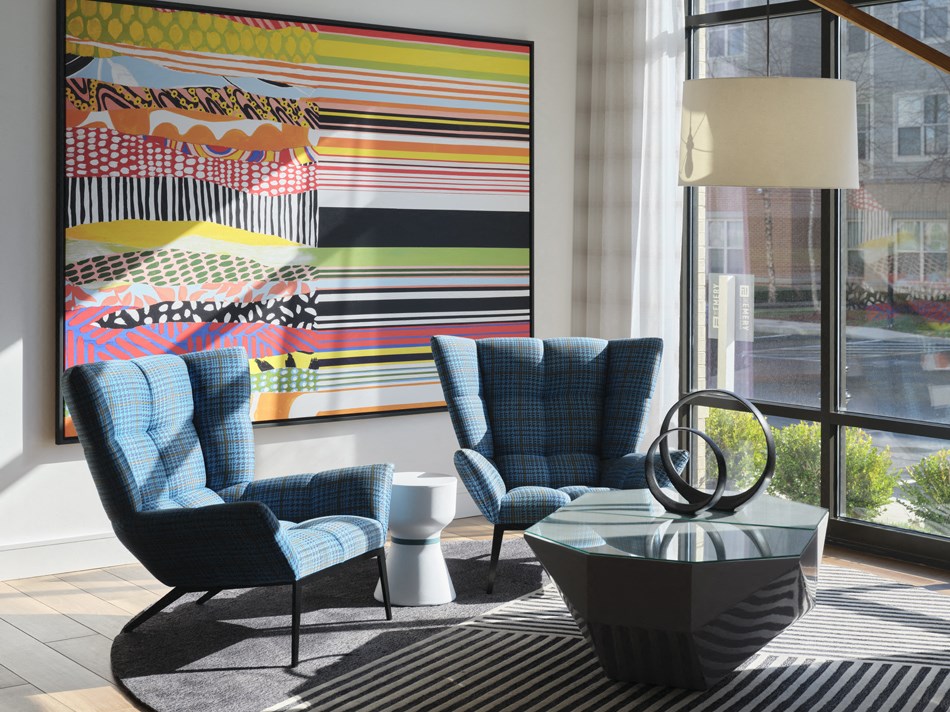 a living room with blue chairs and a large painting on the wall