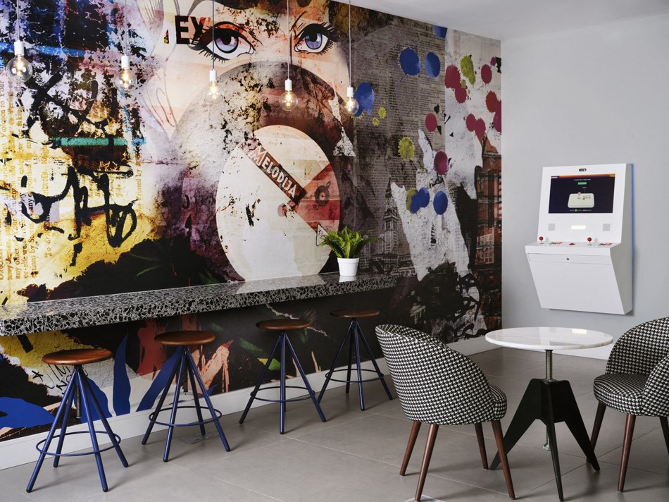 a room with a counter and chairs and a painting on the wall