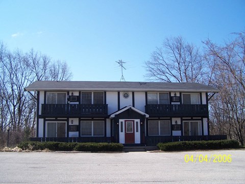 A two-story house with a red door and a balcony on the second floor.