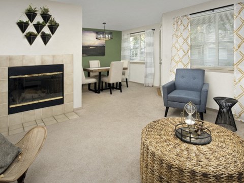 A living room with a fireplace, a chair, a table, and a painting on the wall.