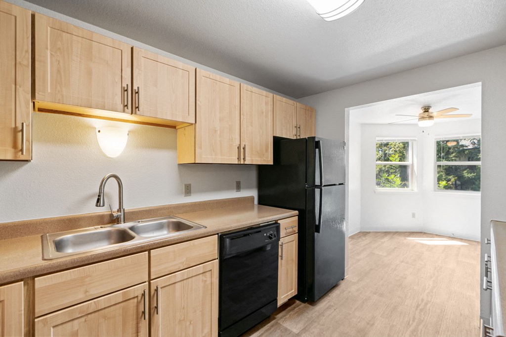 an empty kitchen with wooden cabinets and a black refrigerator