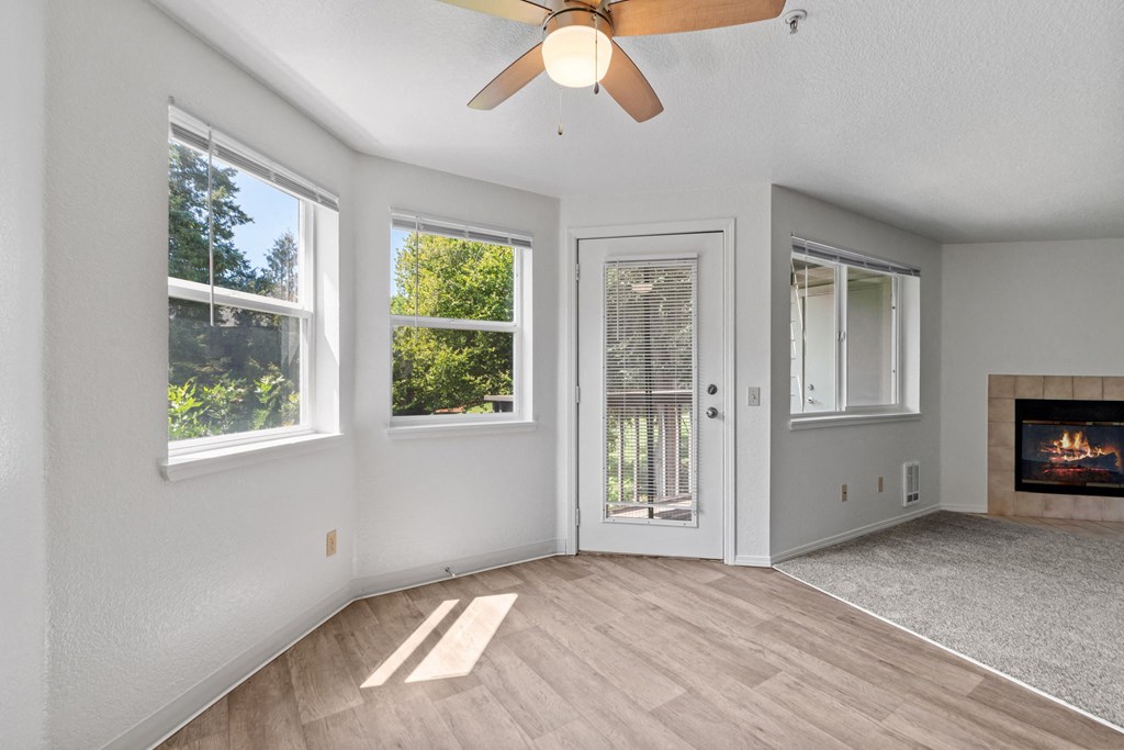 an empty living room with a fireplace and a ceiling fan