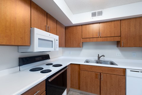 A kitchen with a white counter top and wooden cabinets.