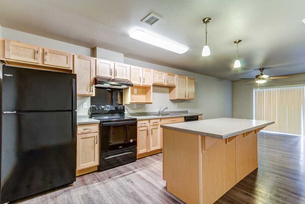 a kitchen with wooden cabinets and a black refrigerator