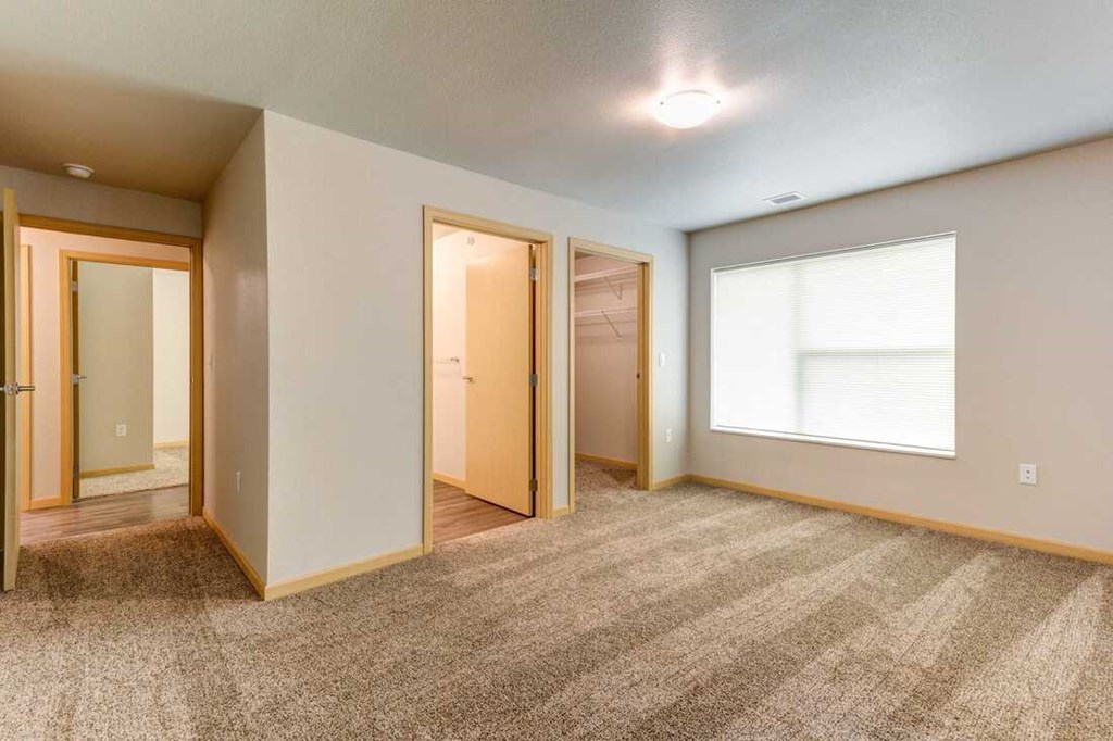 an empty living room with a large window and a door to a closet