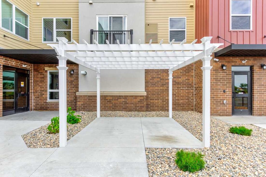 a white pergola in front of a brick building