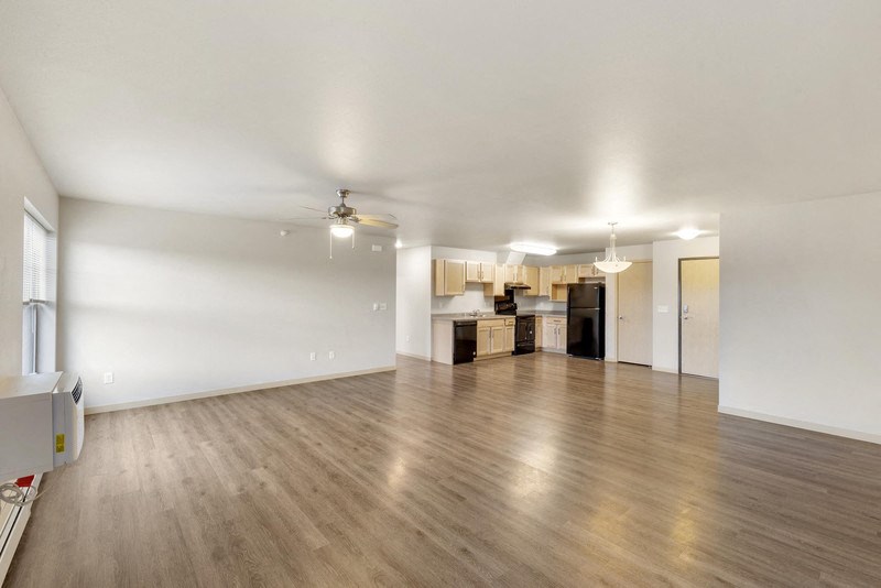 the living room and kitchen of an empty house with wood floors