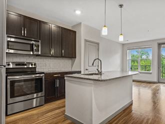 a kitchen with a large island and stainless steel appliances at The Slate at Andover Apartments in Andover MA