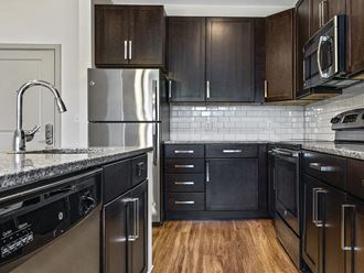 a kitchen with a large island and stainless steel appliances at The Slate at Andover Apartments in Andover MA
