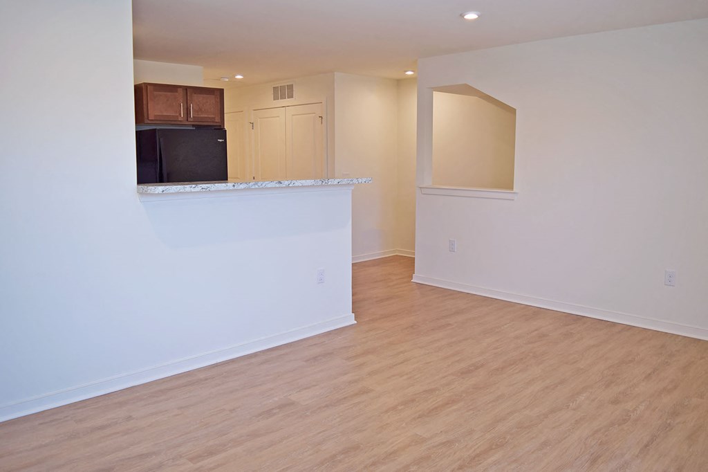 an empty living room and kitchen with a hard wood floor