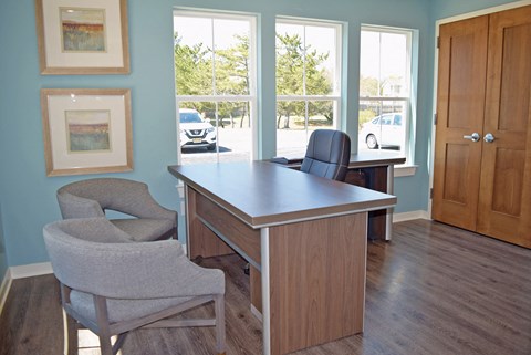 an office with a desk and chairs in front of a window