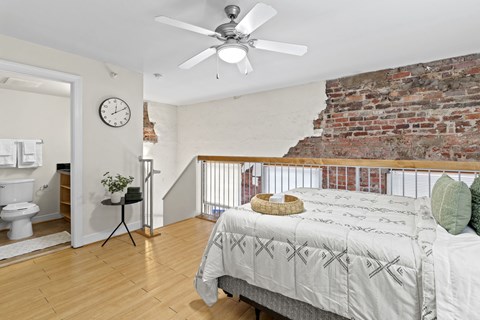 a bedroom with a bed and a brick wall
