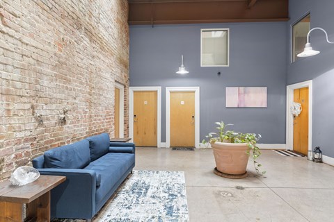 a living room with a blue couch and a brick wall