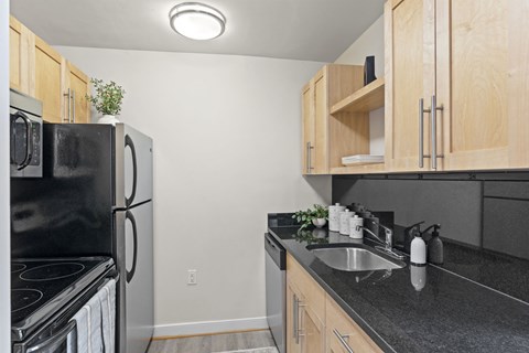 a kitchen with black appliances and black counter tops and wooden cabinets