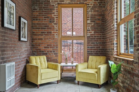 a living room with two yellow chairs and a brick wall