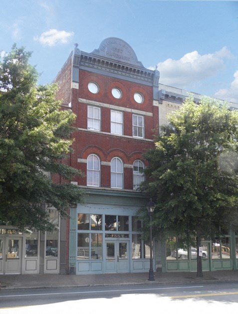 a building on the corner of a street with trees