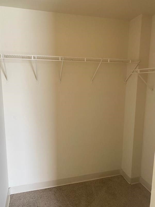 a empty closet with white clothes rails on the wall
