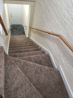 a carpeted stairway with a railing and carpeted stairs