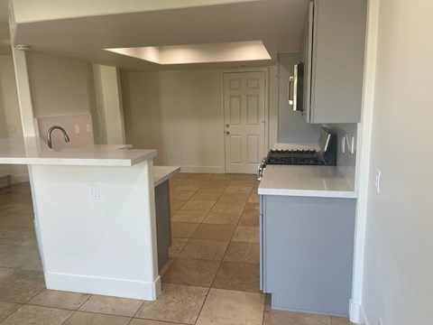 an empty kitchen with white cabinets and a tile floor