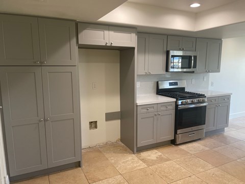 a kitchen with gray cabinets and a stove and a microwave