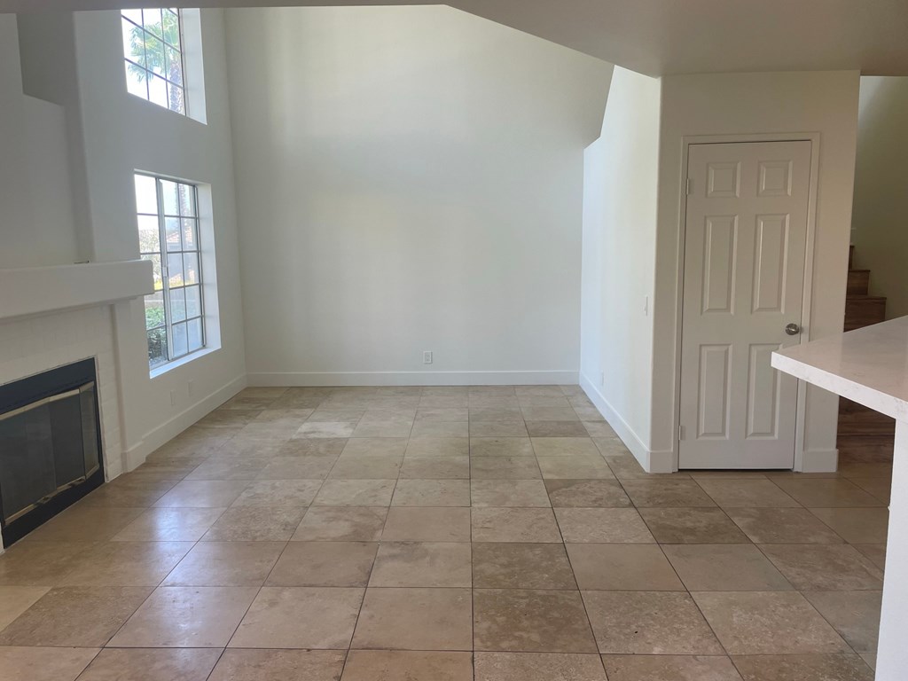 an empty living room with white walls and a tile floor