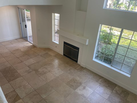 an empty living room with a fireplace and tiled floors