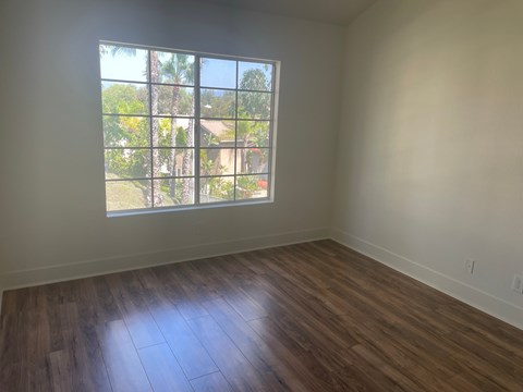 an empty living room with wooden floors and a window