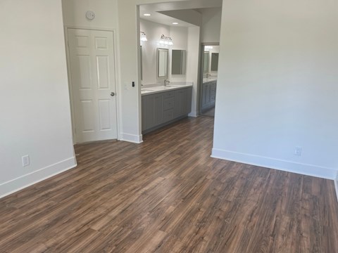 an empty living room with wood flooring and a bathroom