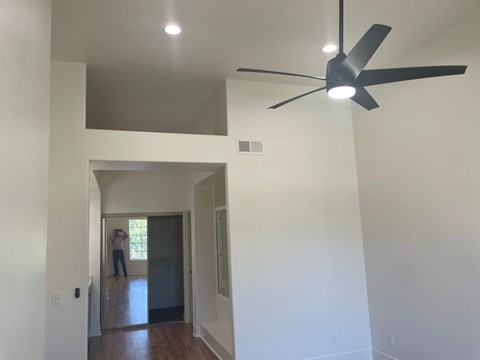 a living room with white walls and a ceiling fan