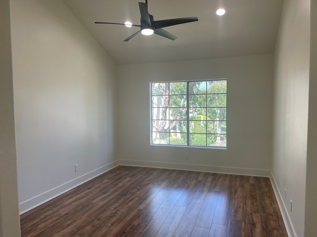 an empty living room with a window and a ceiling fan