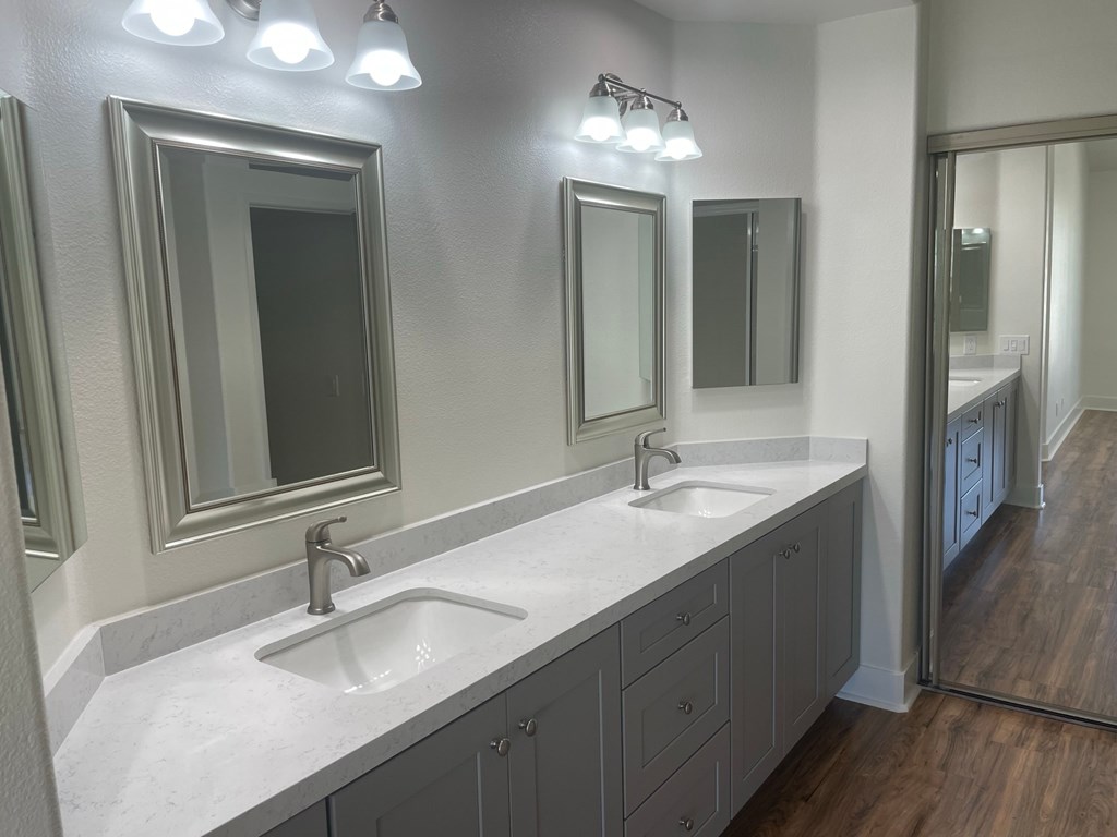 a bathroom with two sinks and three mirrors