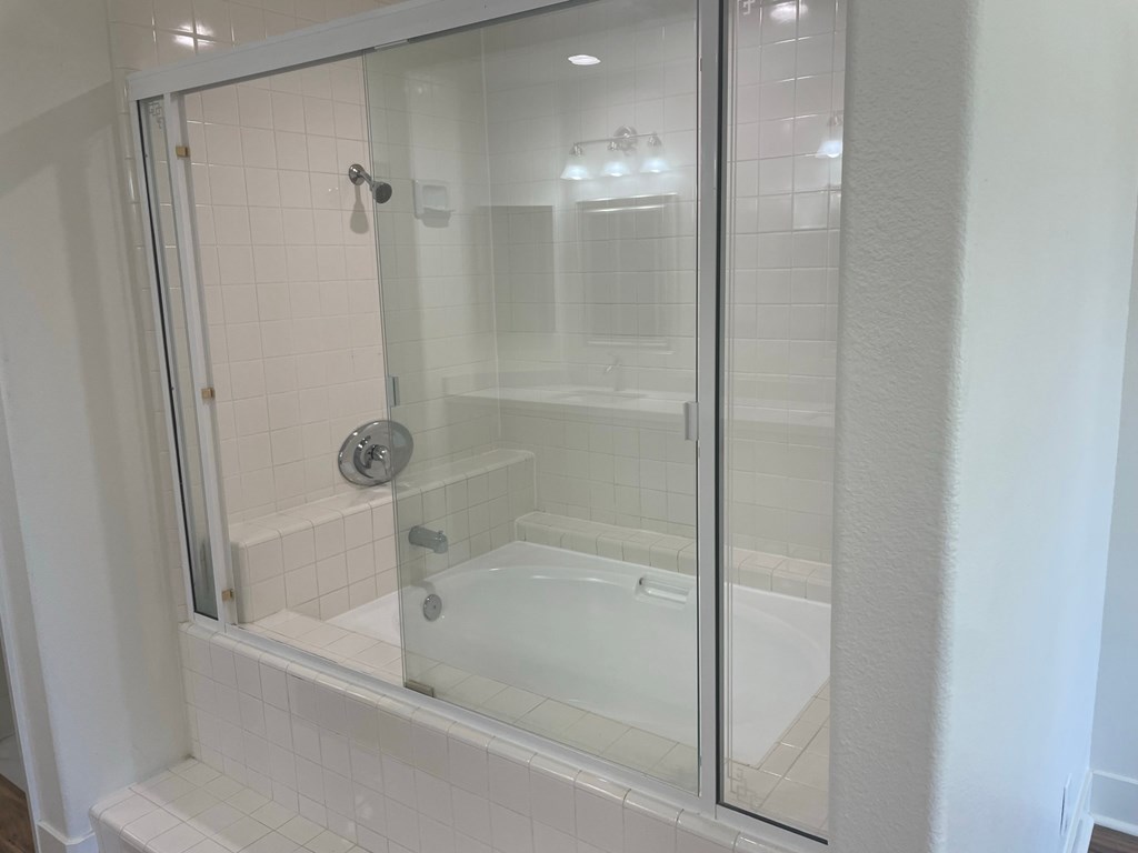 a bathroom with a tub and a glass shower door