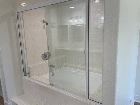 a bathroom with a tub and a glass shower door