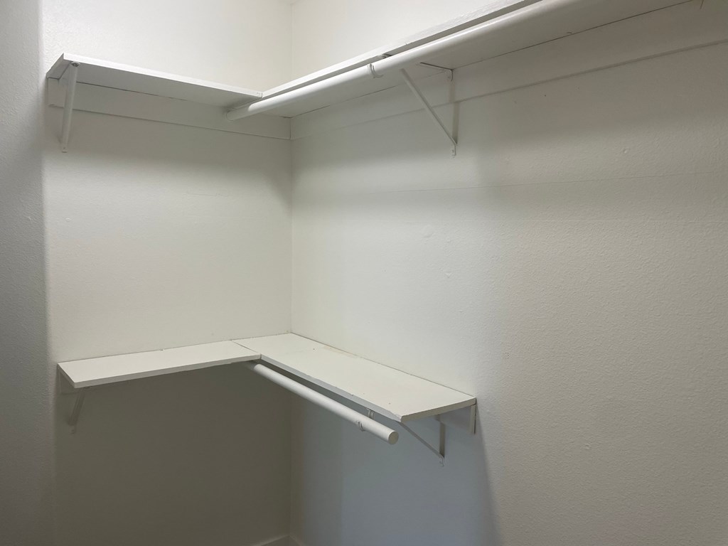 a white closet with a shelf and a white wall