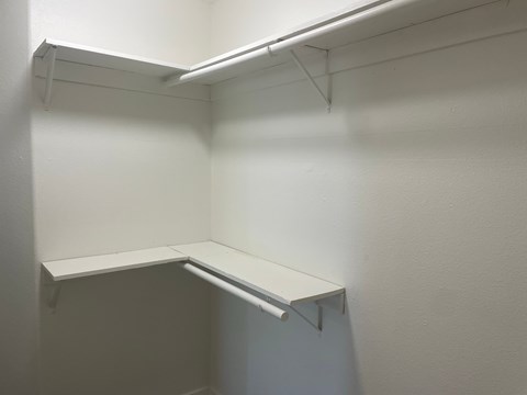a white closet with a shelf and a white wall