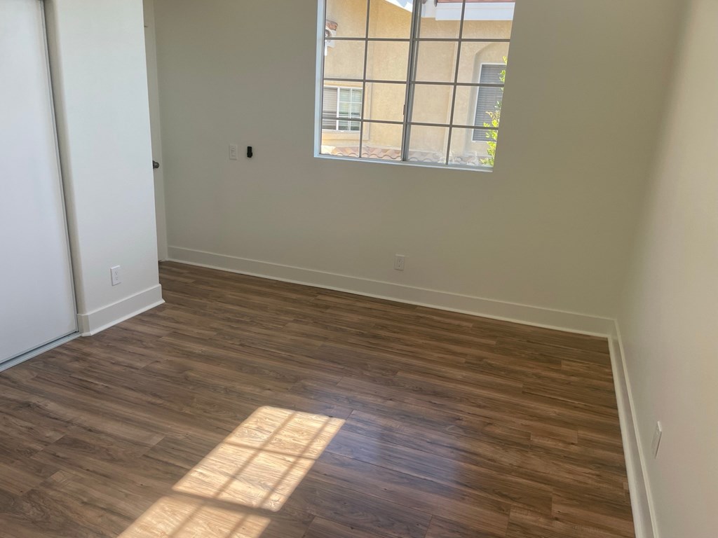 an empty room with wooden floors and a window