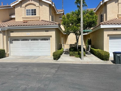 a driveway in front of a house with two garage doors
