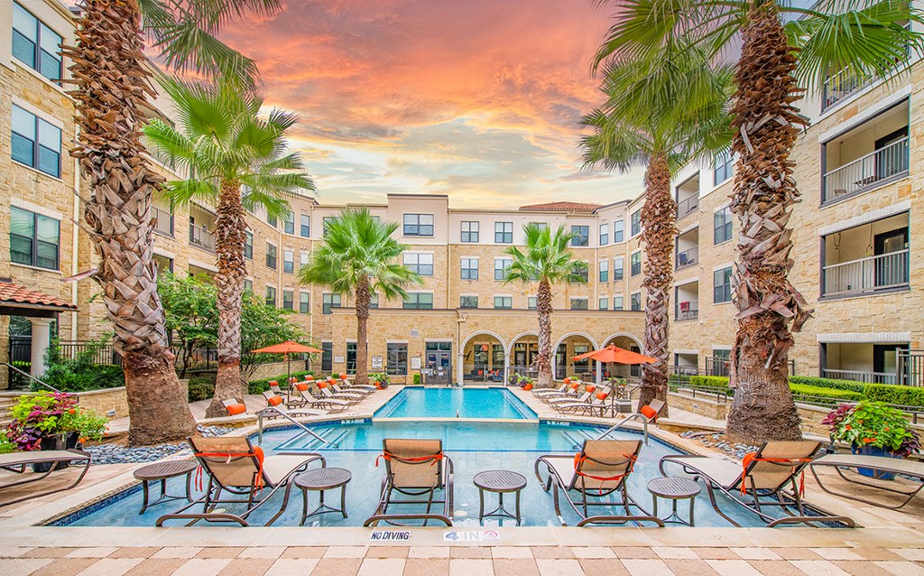 an outdoor pool with chairs and palm trees at an apartment building