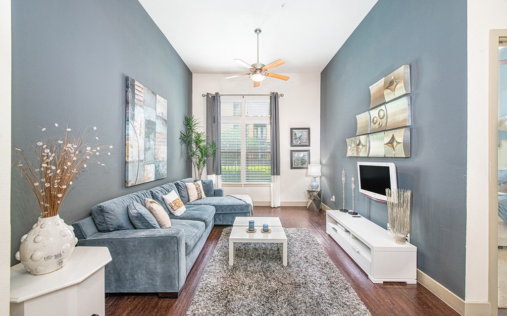 a living room with blue walls and a ceiling fan