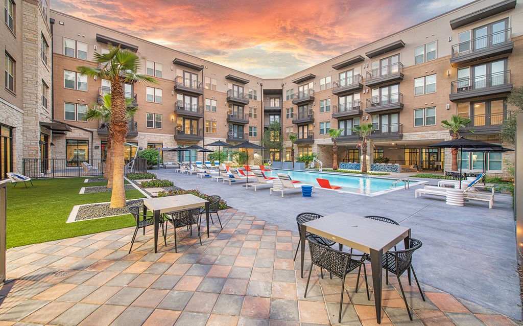 an outdoor patio with tables and chairs near an apartment building