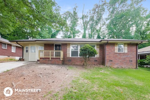 a small brick house with a yard and a porch