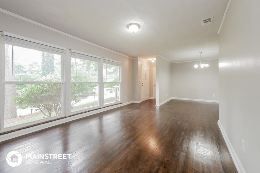 an empty living room with wood floors and large windows