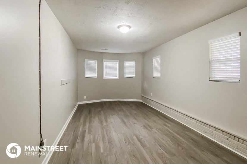 the spacious living room with wood flooring and white walls