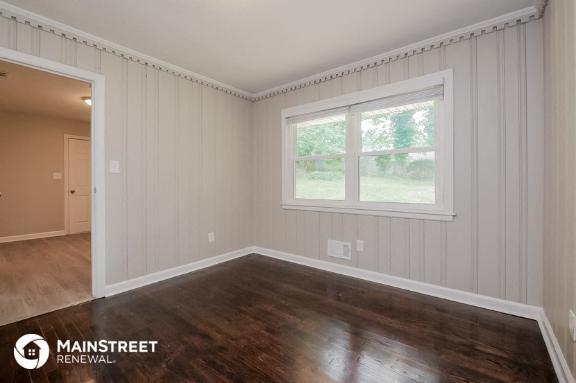 the living room of a home with wood floors and a window
